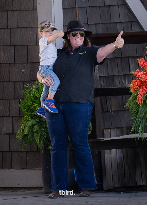 A woman holding a small child, both giving a thumbs-up.