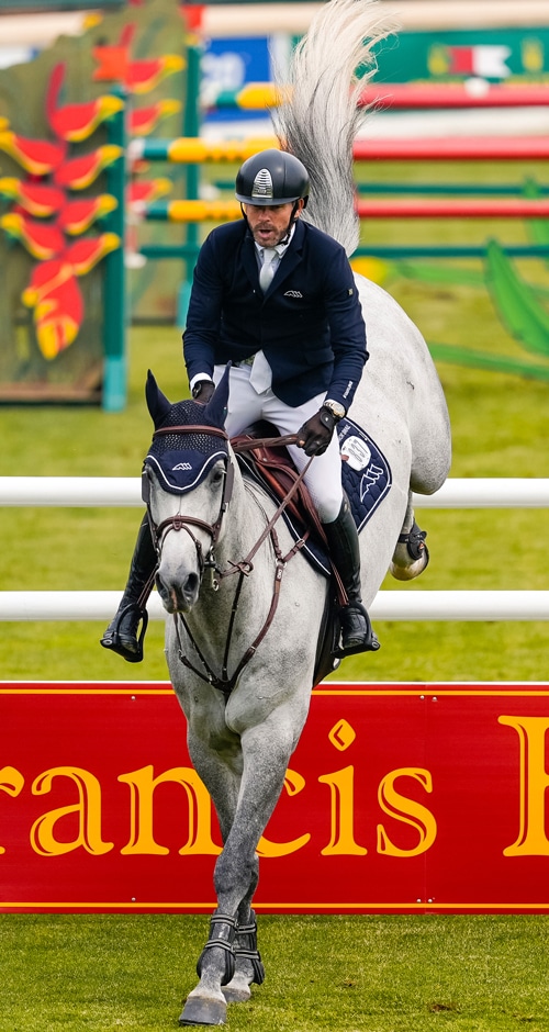 A man jumping a grey horse over a fence at Spruce Meadows.