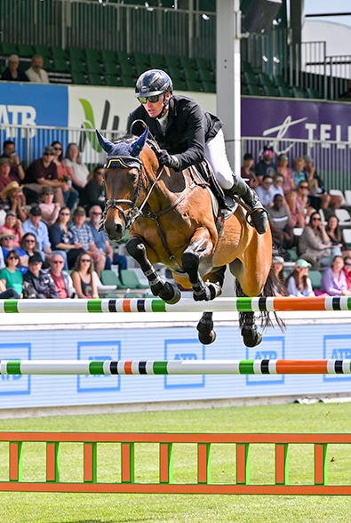 A man jumping a bay horse over a fence at Spruce Meadows.