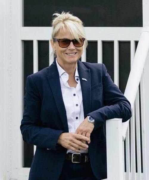 A blond woman wearing sunglasses, standing on some steps.