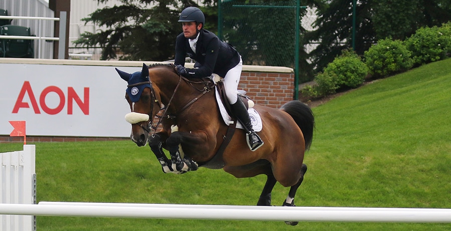A man jumping a bay horse over a fence at Spruce Meadows.