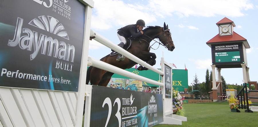 A man jumping a bay mare over a fence at Spruce Meadows.