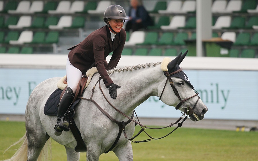 A woman patting a grey mare.