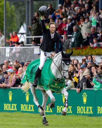 A man celebrating on a galloping grey horse.