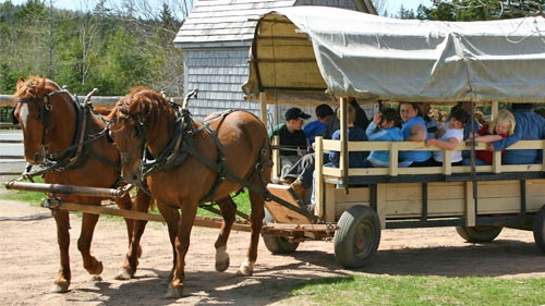 Two horses pulling a wagon full of people.