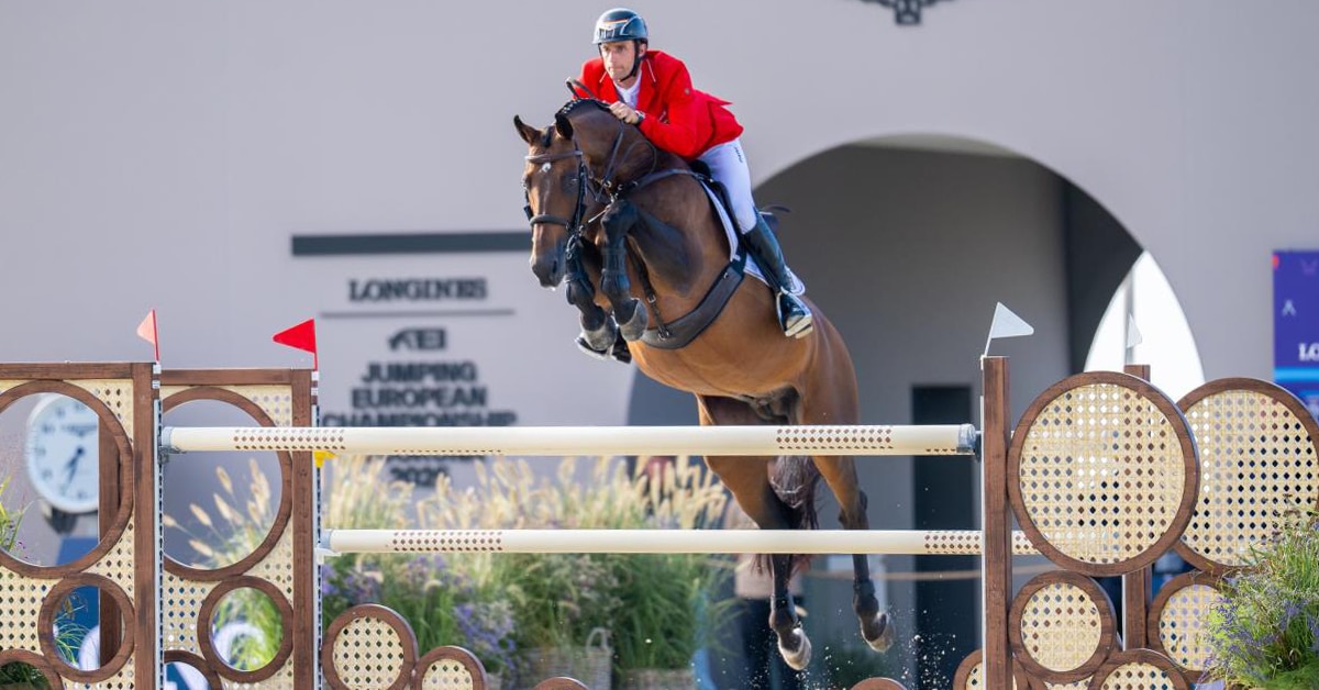A man jumping a bay horse over a fence in Spain.