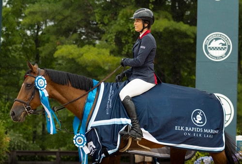 A woman on a bay horse during a prize-giving ceremony.