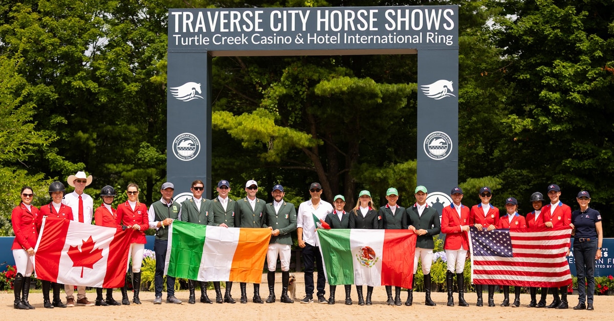 A group of four teams holding flags at the Traverse City Horse Show.