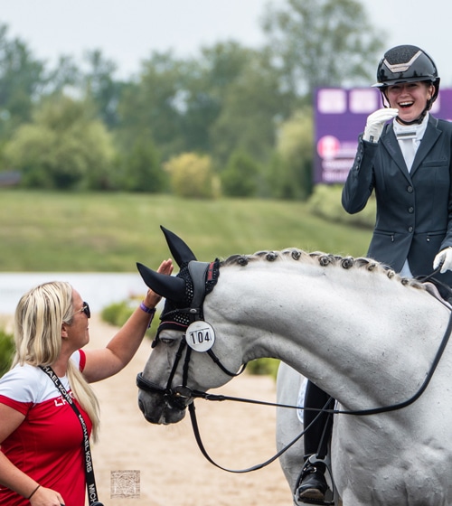 A smiling teen on a grey horse.