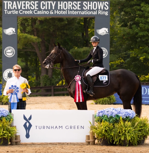 A woman on a dark bay horse accepting the Leafing Lady Rider award.