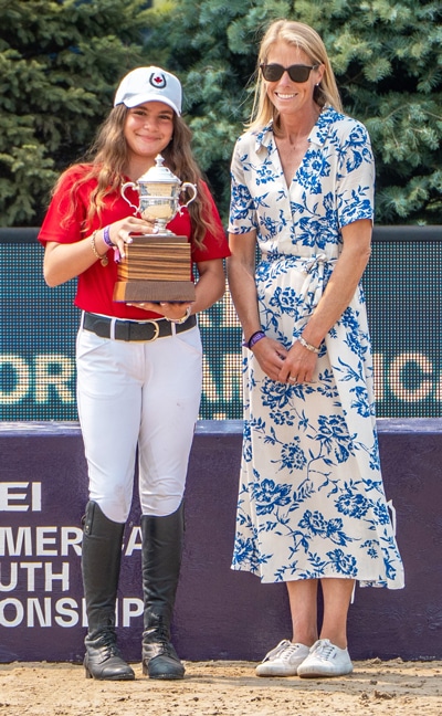 A teenage girl holding a silver trophy.