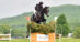 A woman riding a bay horse over a cross-country fence at Bromont.