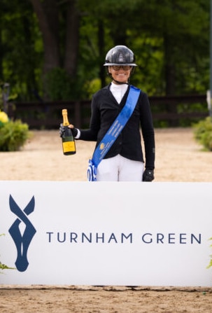 A smiling woman with a bottle of champagne.