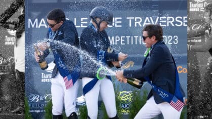 Three people of a podium, spraying champagne.