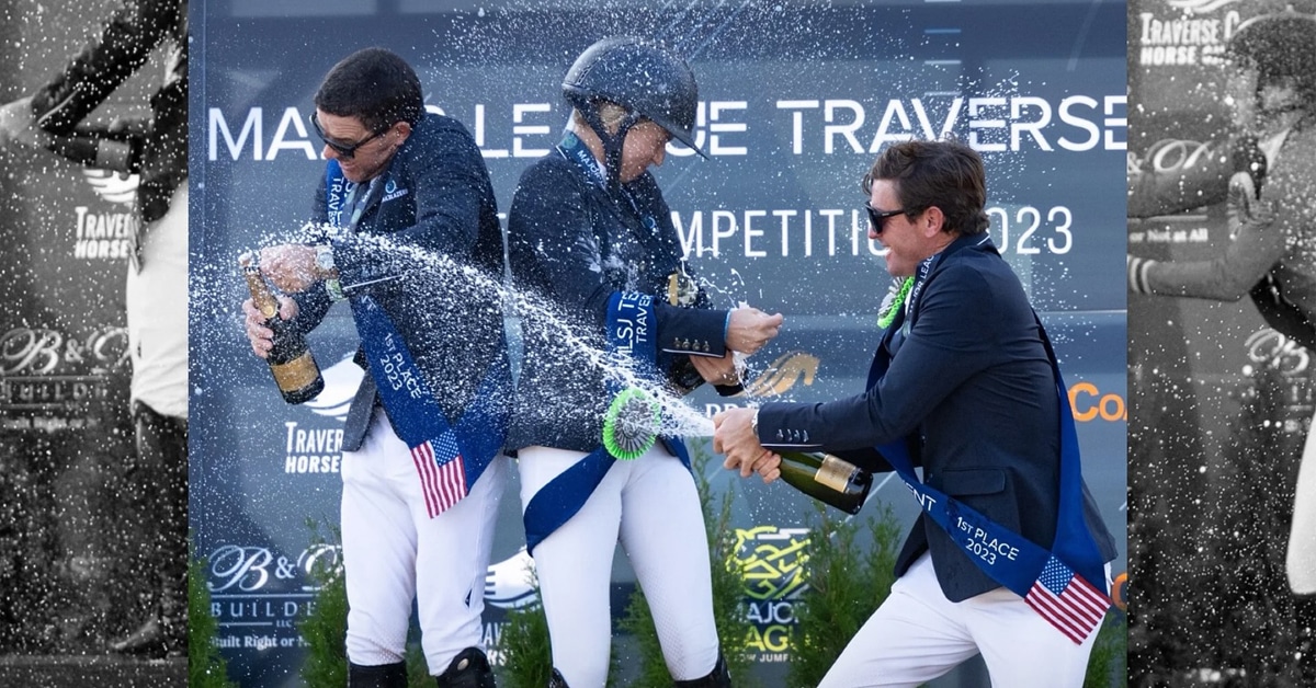 Three people of a podium, spraying champagne.