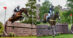 Two women on bay horses jumping cross-country fences in Scotland.