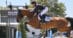 A man jumping a bay horse over a fence in the Hamptons.