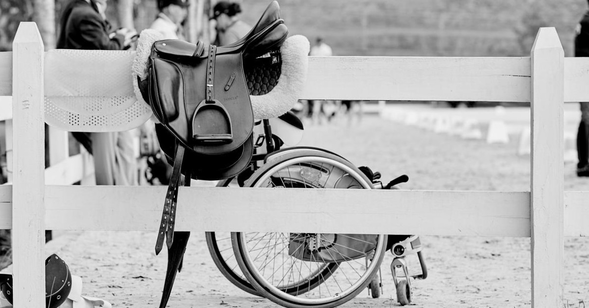Black-and-white photo of a saddle and wheelchair.