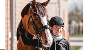 A woman patting a bay dressage horse.