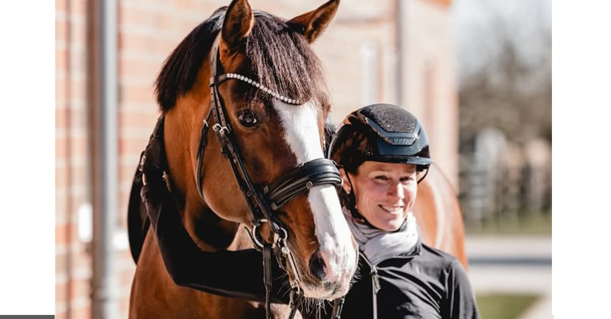 A woman patting a bay dressage horse.