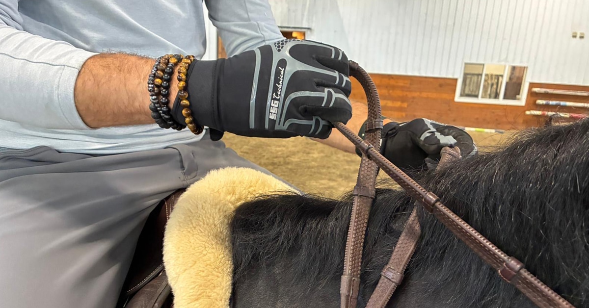 A closeup of a man's hands demonstrating an indirect rein.