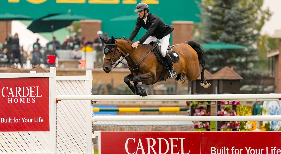 A man jumping a bay horse over a fence at Spruce Meadows.