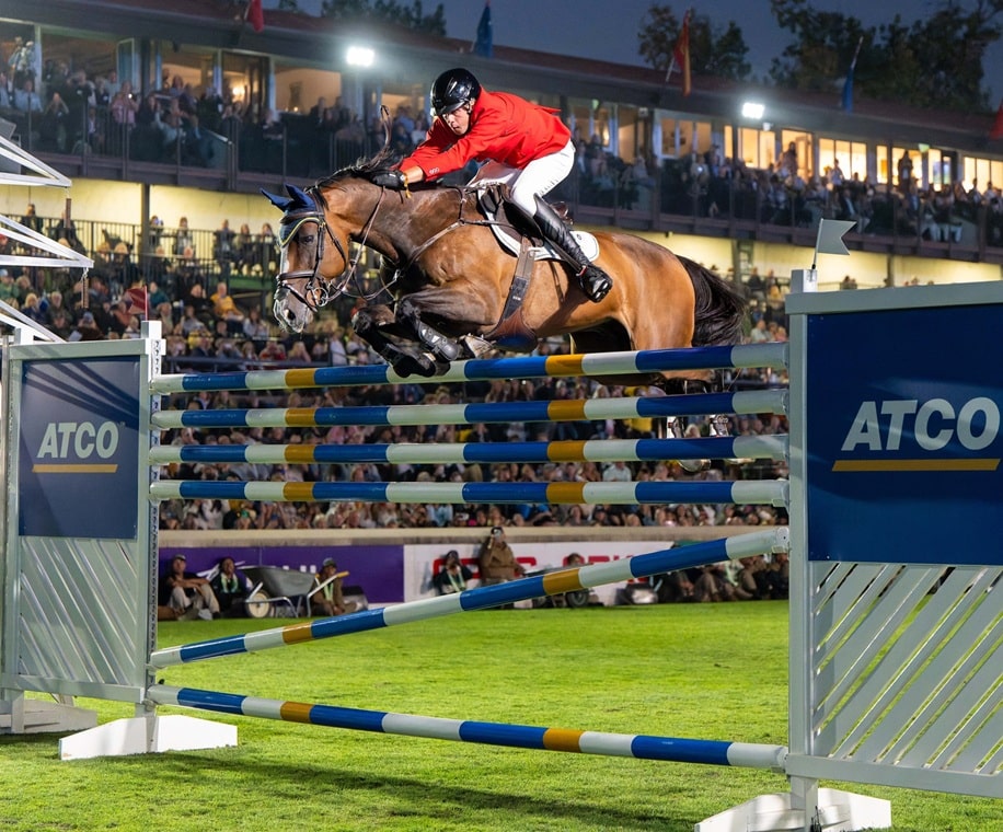 A man jumping a bay horse over a very big fence at Spruce Meadows.