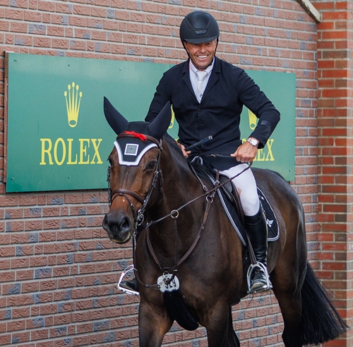 A smiling man on a dark bay horse.