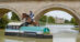 A woman jumping abay horse over a water jump with a castle in the background.