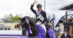 A man on a black dressage horse, waving and smiling.
