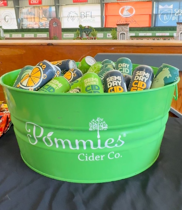 A green bucket full of Pommies Cider.