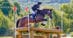 A young woman on a bay horse jumping a cross-country fence at Bromont.