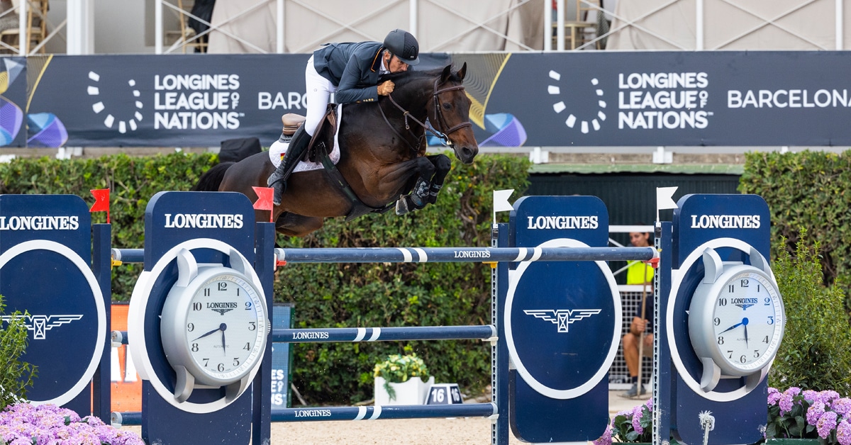 A man jumping a bay horse over a fence in Barcelona.