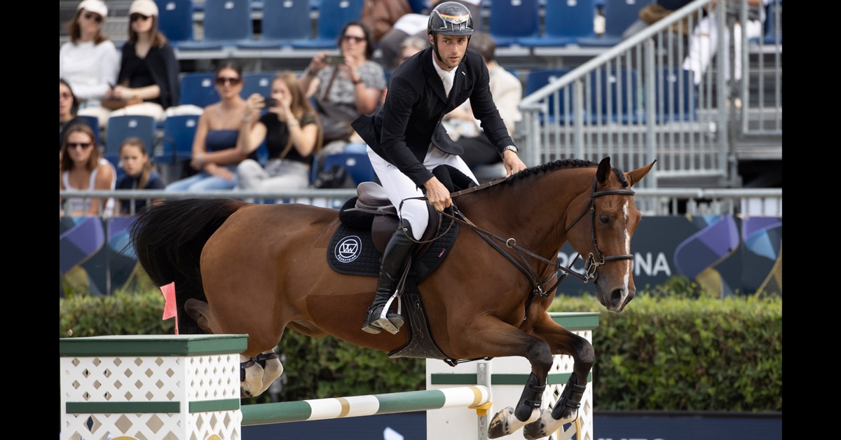 A man on a bay horse jumping a fence in Spain.