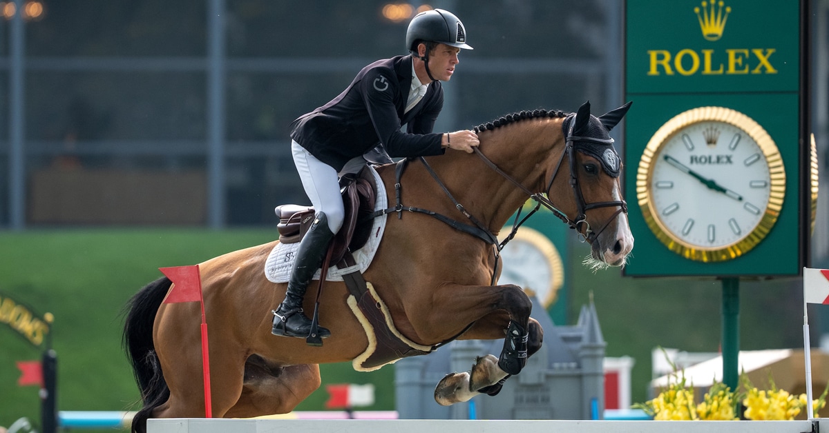 A man jumping a bay horse over a fence at Spruce Meadows.