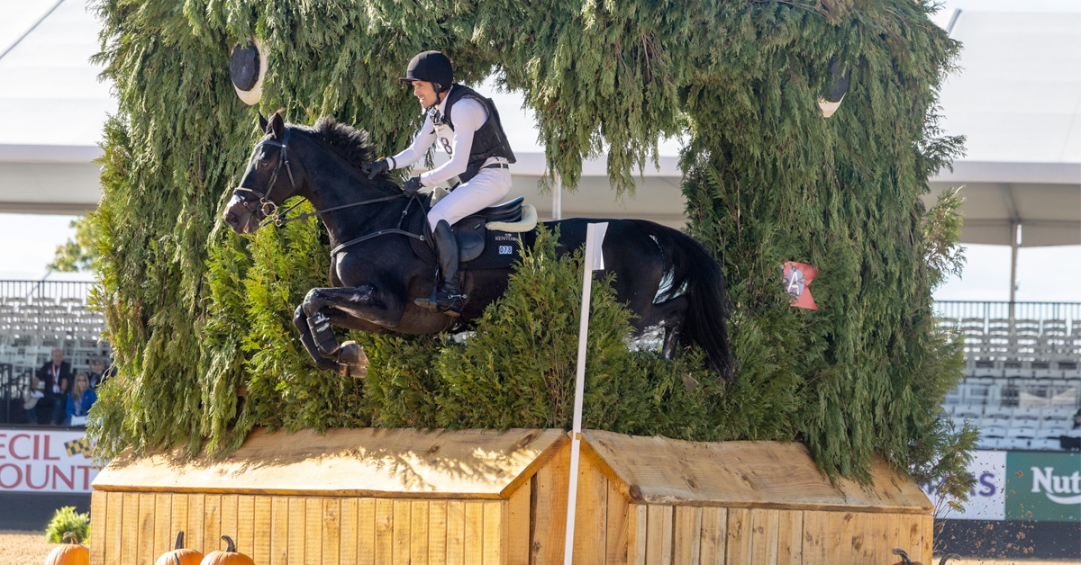 A man jumping a black horse over a cross-country fence in Maryland.