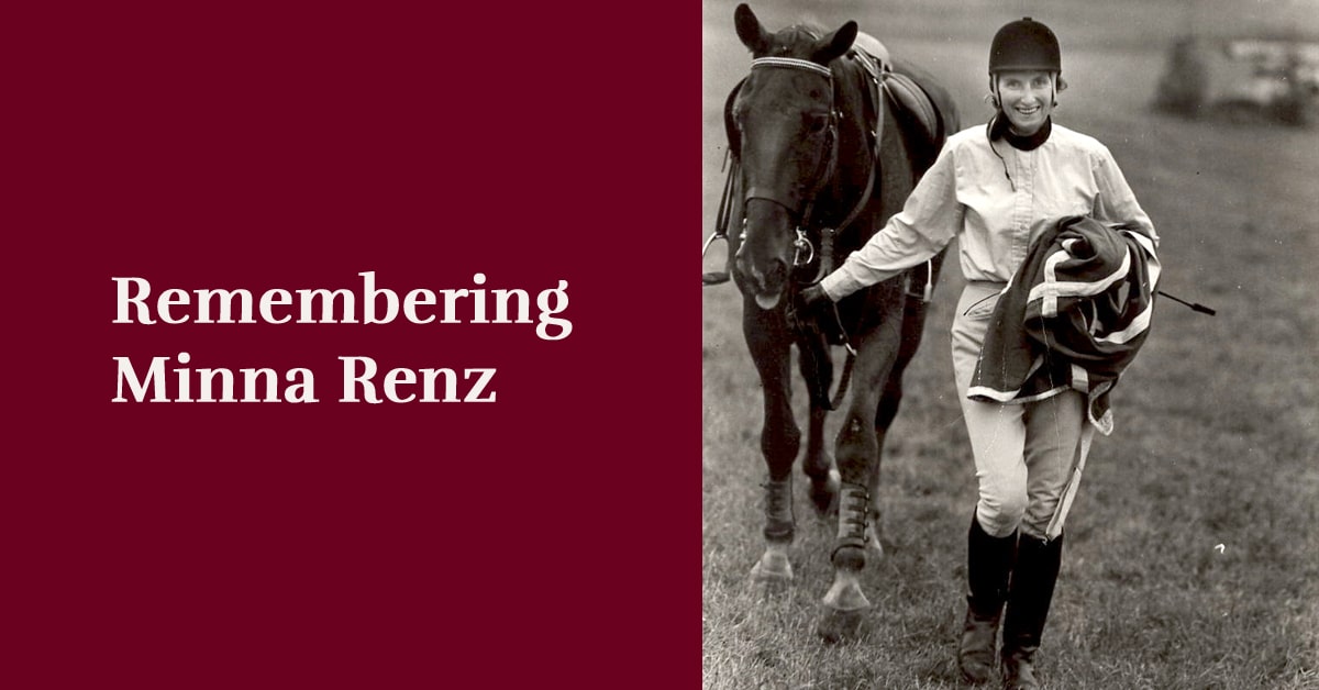 An old black-and-white photo of a smiling woman leading a horse.