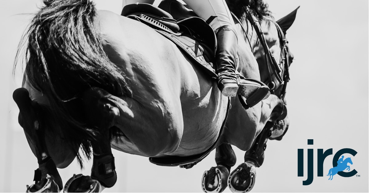 Black-and-white image of a horse and rider jumping a fence.