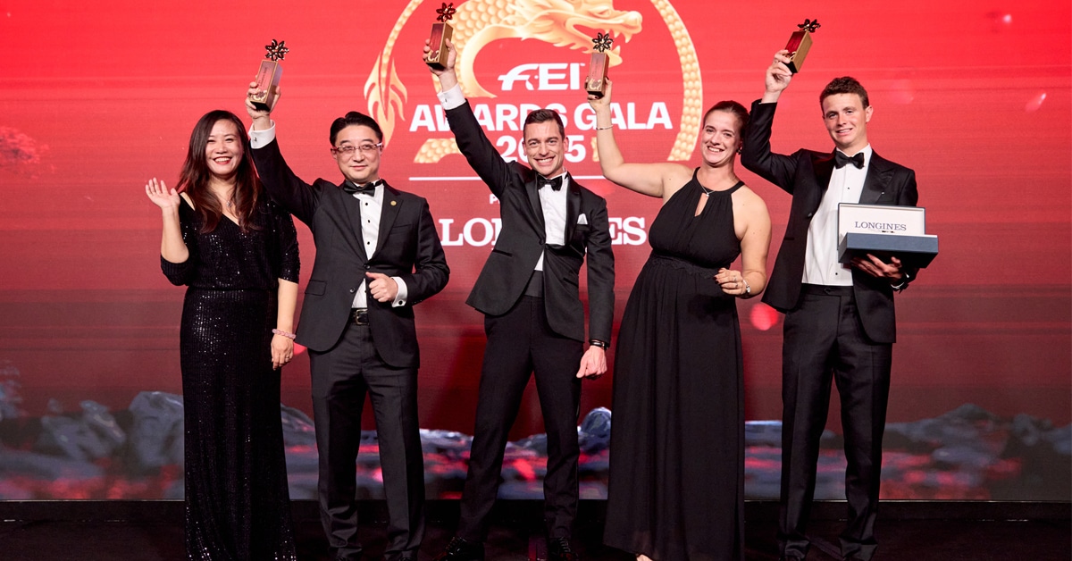 A group of people on a stage holding trophies.