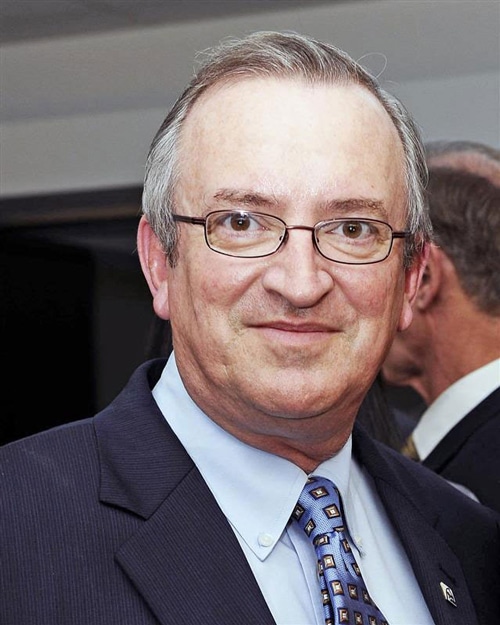 Headshot of a man wearing glasses and a suit.