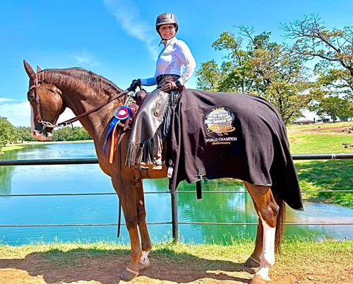 A smiling woman on a horse wearing a championship cooler.