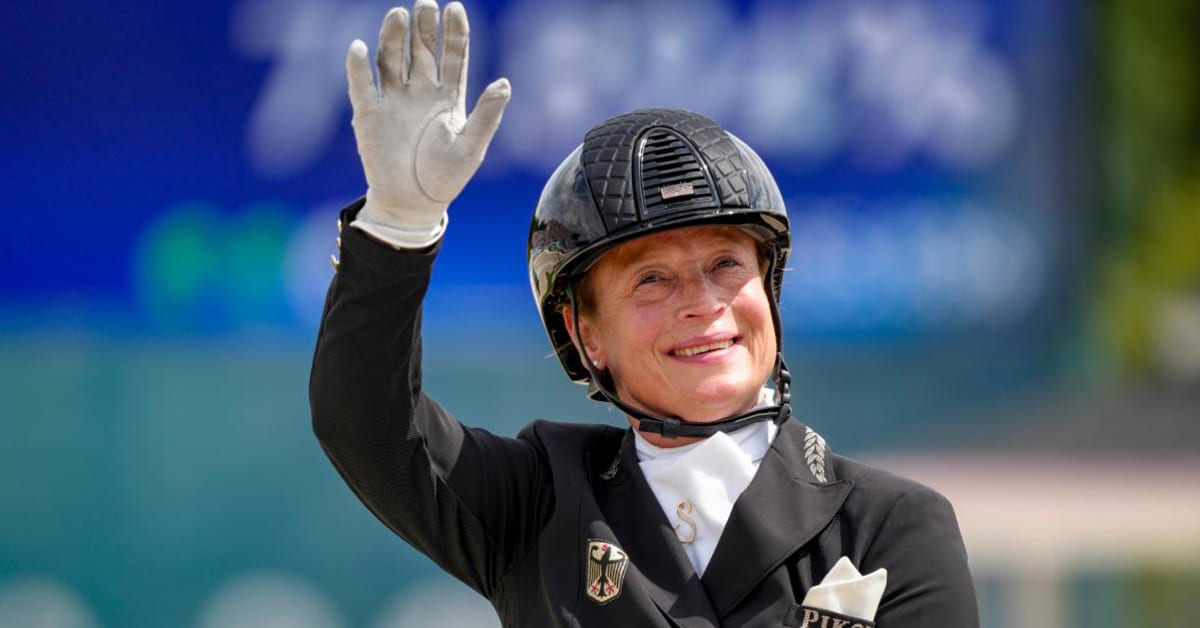 A dressage rider waving to the crowd.
