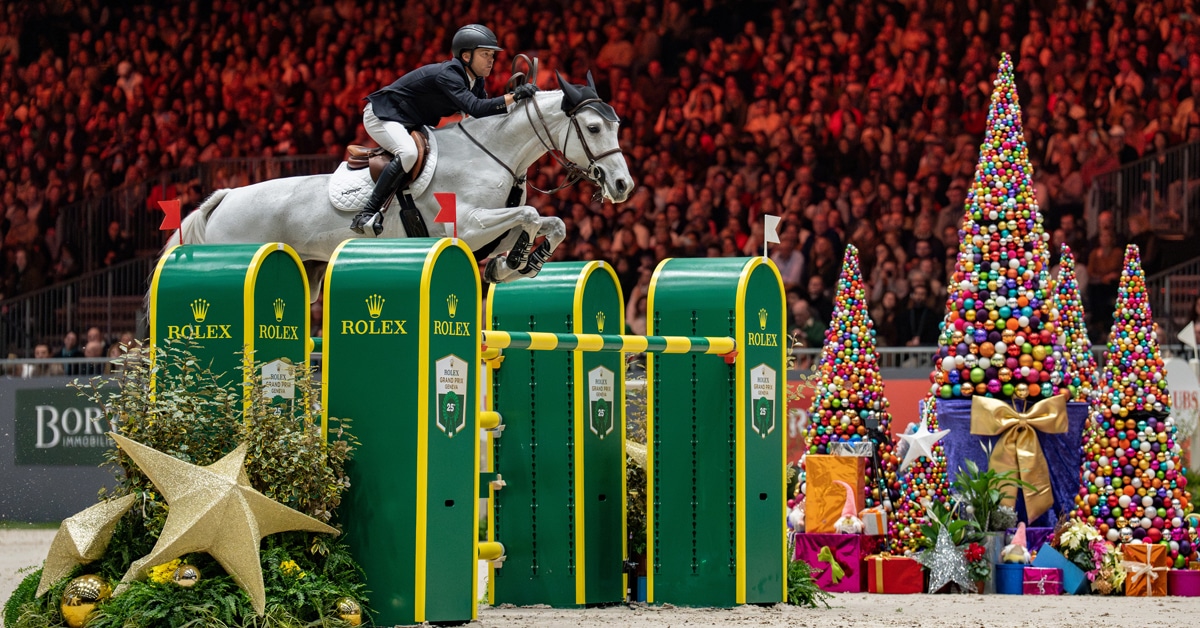 A man jumping a Rolex fence on a grey mare.