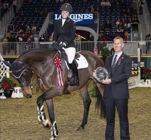 A man making a presentation at the Royal to a woman on a dark bay horse.