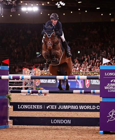 A man jumping a fence on a bay horse in London.