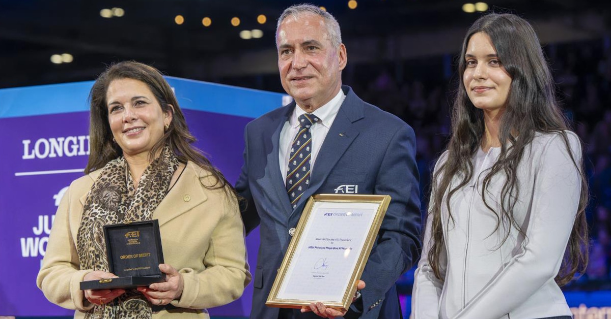 A woman getting an award from a man and a younger woman.