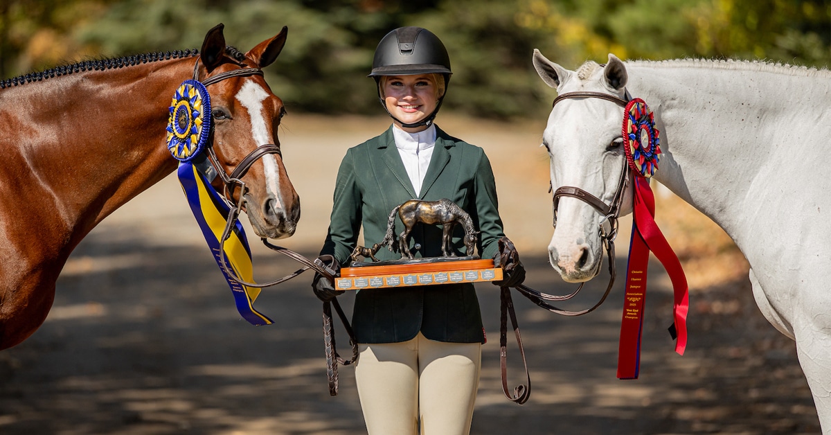 A teenage girl with a trophy and two horses.