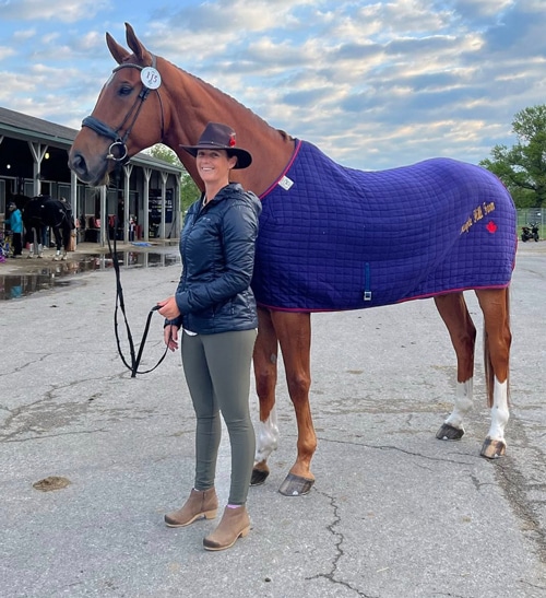 A tall chestnut being held by a smiling woman.