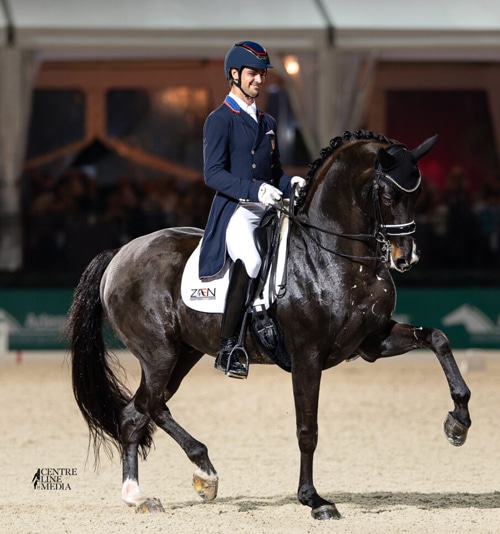 A man riding a black dressage horse in an arena in Florida.