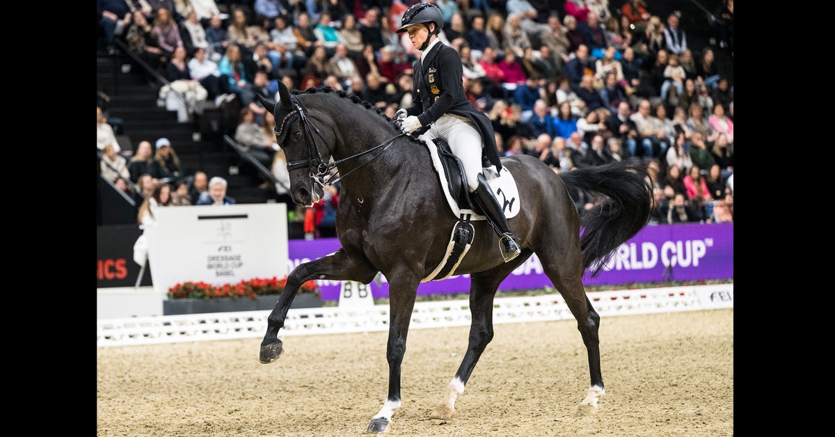 A woman riding a black dressage horse during a test in Switzerland.